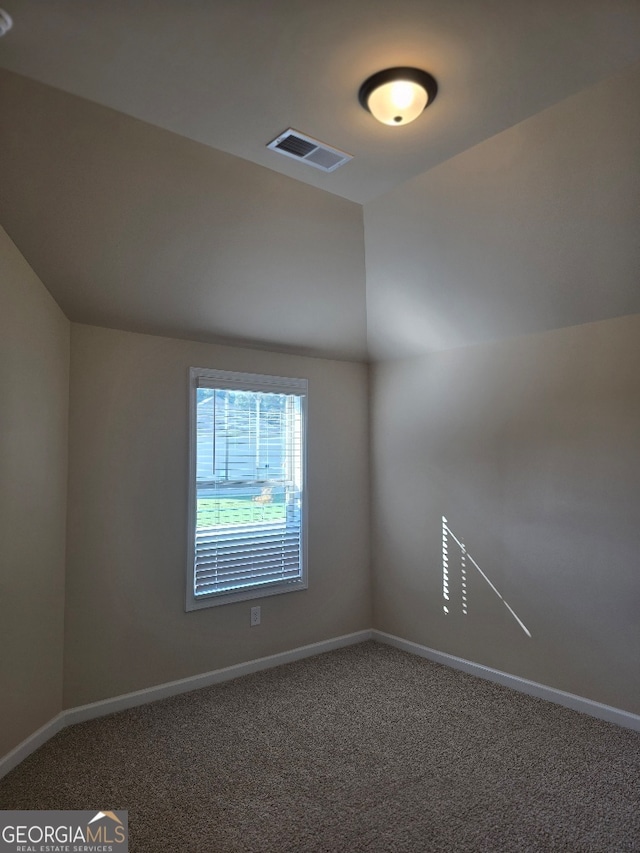 spare room with carpet floors and vaulted ceiling