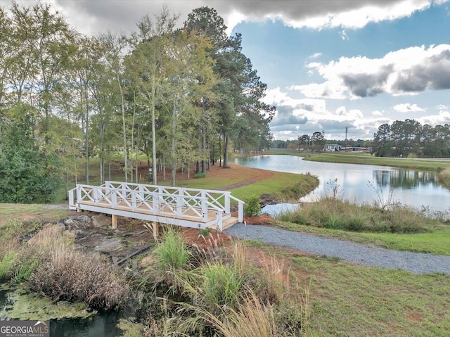 view of property's community with a water view and a lawn