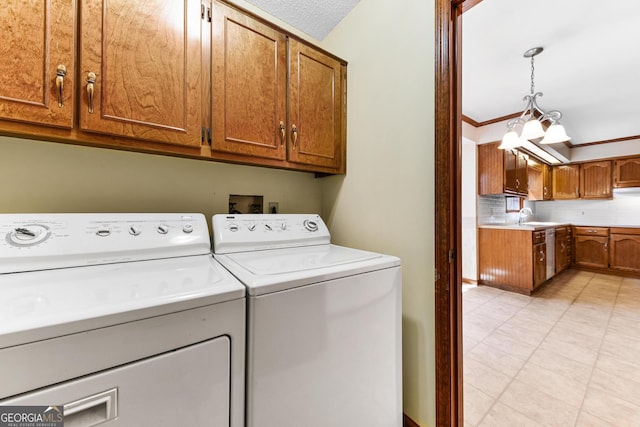 laundry area with light tile floors, a notable chandelier, cabinets, washing machine and dryer, and sink