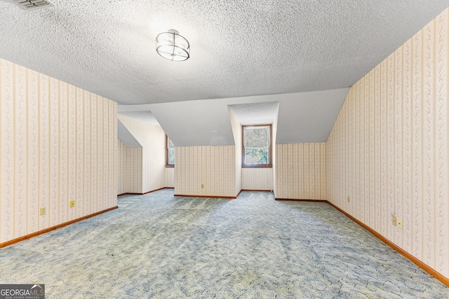 bonus room featuring a textured ceiling, light colored carpet, and lofted ceiling