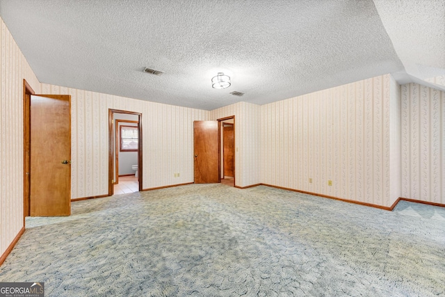 unfurnished room featuring light colored carpet and a textured ceiling