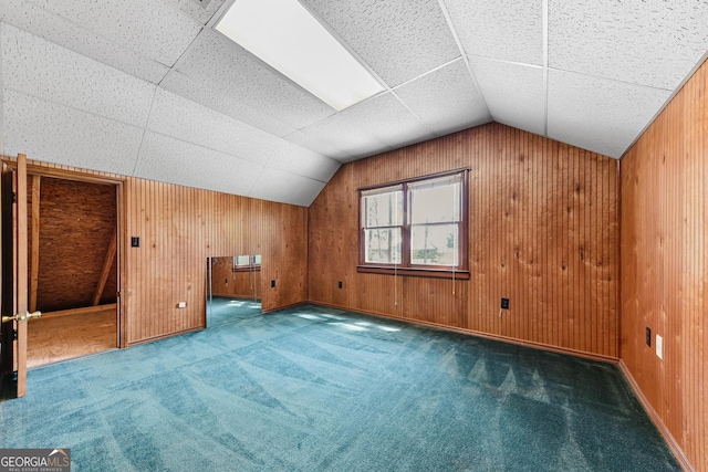 bonus room with dark carpet, wood walls, and vaulted ceiling