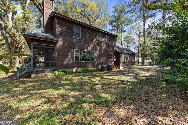 back of house featuring a sunroom, central AC unit, and a yard