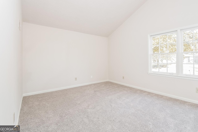 carpeted empty room with lofted ceiling and baseboards