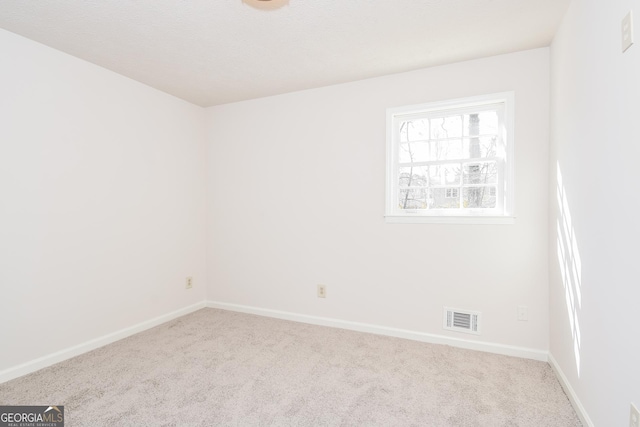 unfurnished room with light carpet, visible vents, and baseboards