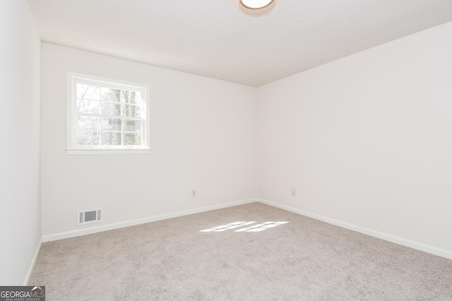 carpeted empty room with visible vents, a textured ceiling, and baseboards