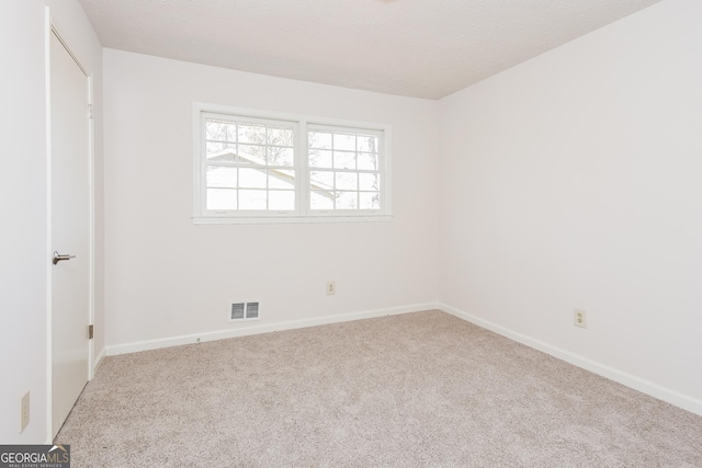 empty room featuring a textured ceiling, carpet floors, visible vents, and baseboards