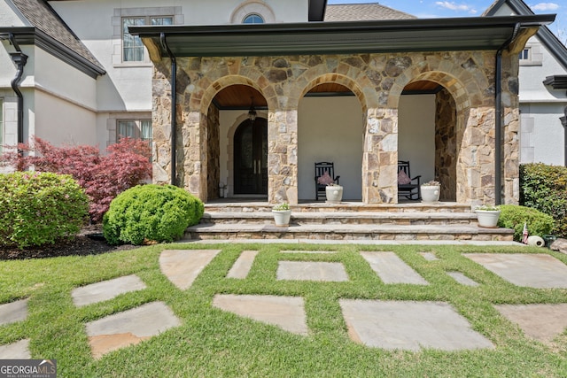 113 Hawks Ct, Ball Ground, GA 30107 - view of exterior entry featuring stone siding, covered porch, stucco siding, and a yard