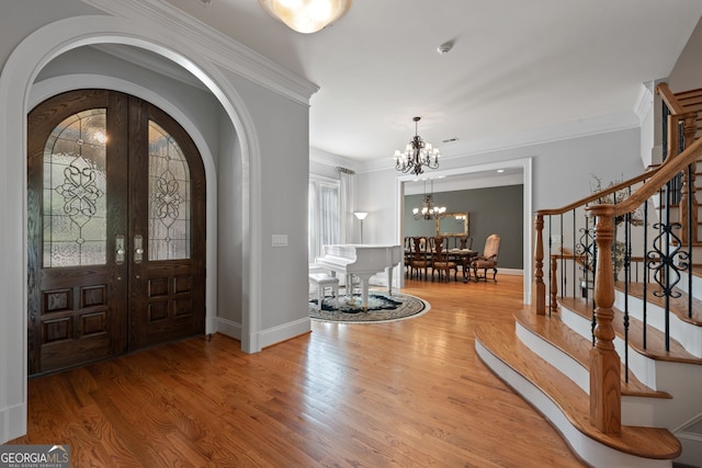 113 Hawks Ct, Ball Ground, GA 30107 - entryway with arched walkways, a chandelier, wood finished floors, stairs, and crown molding