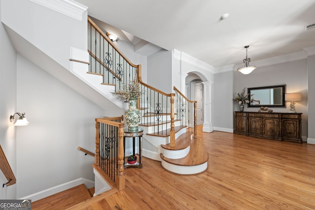 entrance foyer with ornamental molding, light wood-type flooring, and ornate columns