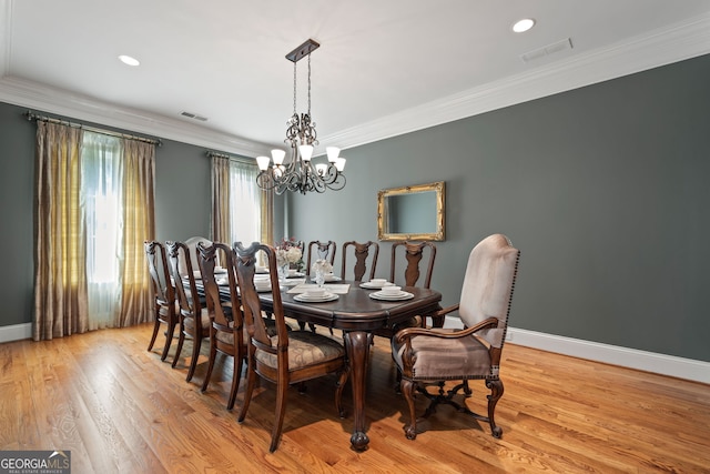 dining area featuring an inviting chandelier, light hardwood / wood-style floors, and crown molding