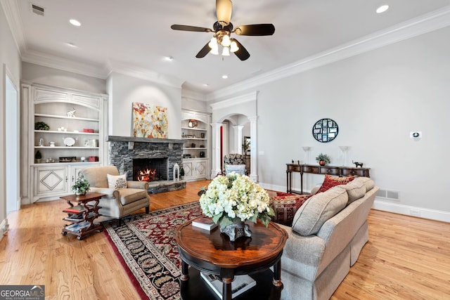 113 Hawks Ct, Ball Ground, GA 30107 - living area with decorative columns, a ceiling fan, ornamental molding, a stone fireplace, and light wood-style floors