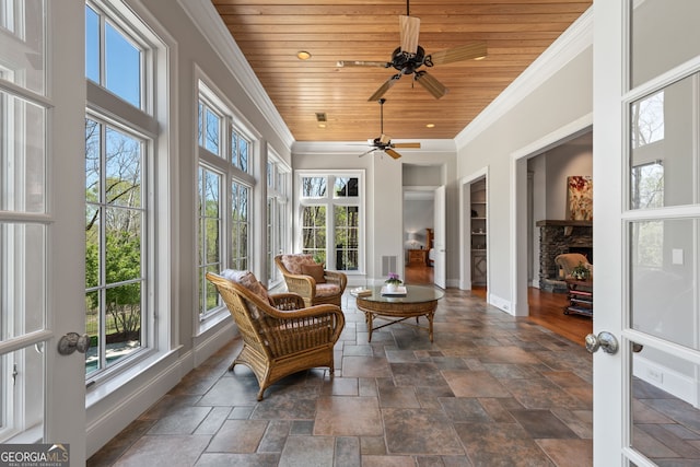 sunroom / solarium with ceiling fan, a fireplace, and wood ceiling