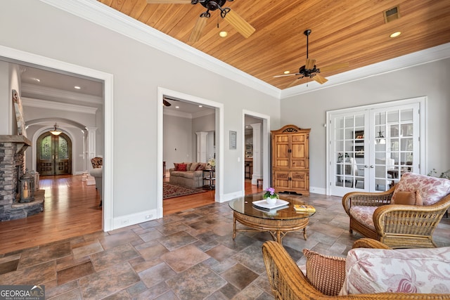 living area featuring french doors, a fireplace, ornamental molding, ceiling fan, and dark tile floors