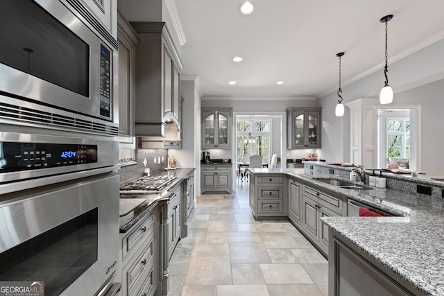 kitchen featuring backsplash, light tile floors, hanging light fixtures, sink, and appliances with stainless steel finishes