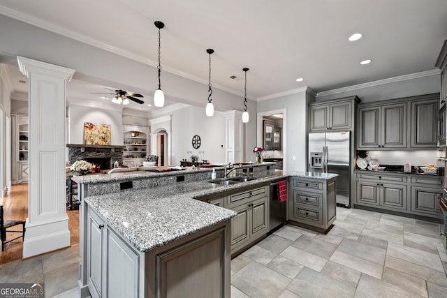 kitchen with stainless steel appliances, ceiling fan, a stone fireplace, light tile floors, and pendant lighting