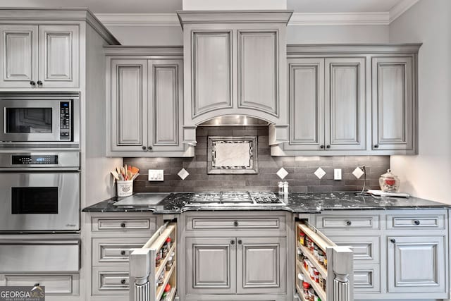 113 Hawks Ct, Ball Ground, GA 30107 - kitchen featuring appliances with stainless steel finishes, a warming drawer, ornamental molding, tasteful backsplash, and dark stone counters