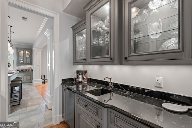 bar featuring ornamental molding, dark stone countertops, ornate columns, sink, and light tile floors