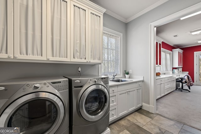 laundry area featuring washing machine and clothes dryer, crown molding, light tile floors, sink, and cabinets