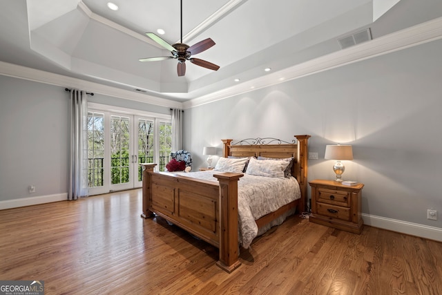 bedroom featuring ceiling fan, a tray ceiling, french doors, and wood-type flooring