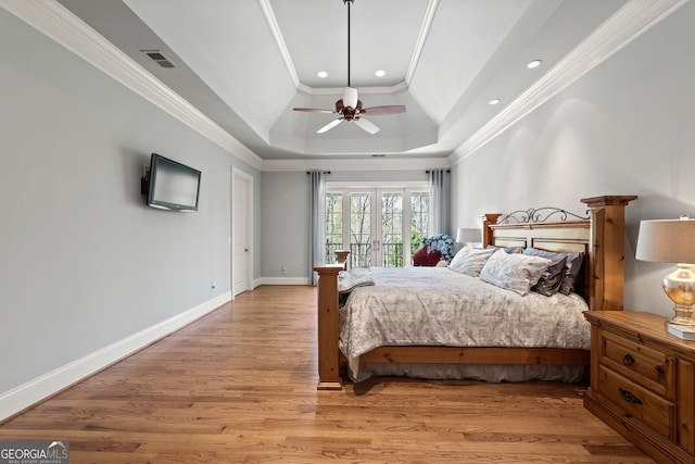 bedroom with ceiling fan, a tray ceiling, crown molding, hardwood / wood-style floors, and french doors