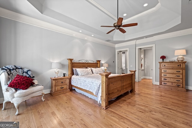 bedroom featuring ceiling fan, ornamental molding, light hardwood / wood-style flooring, and a raised ceiling