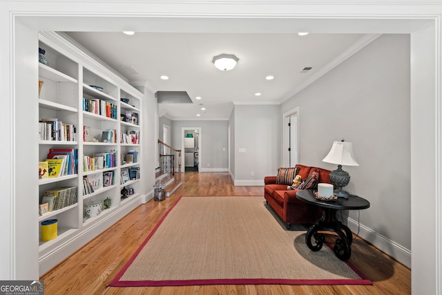 living area with ornamental molding and light hardwood / wood-style flooring