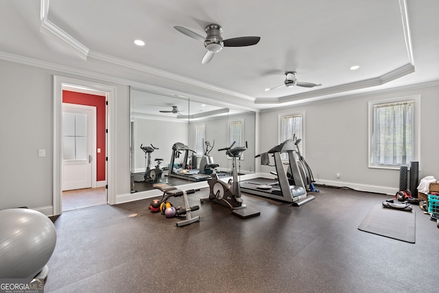 exercise room with ornamental molding, ceiling fan, and a raised ceiling