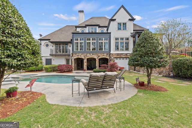 rear view of property featuring a patio, a garage, a balcony, and a yard