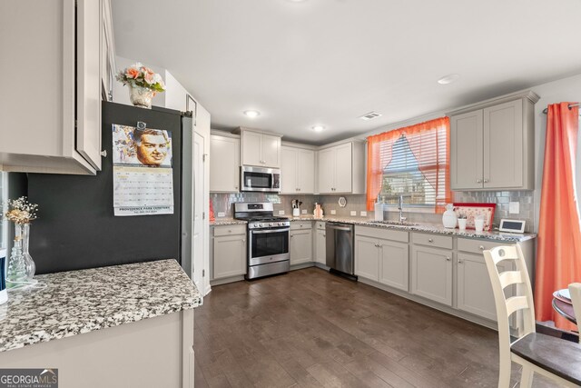 kitchen with appliances with stainless steel finishes, backsplash, dark wood-type flooring, and sink