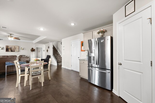 kitchen featuring light stone countertops, stainless steel refrigerator with ice dispenser, ceiling fan, and dark wood-type flooring