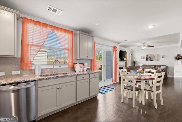 kitchen featuring stainless steel dishwasher, dark wood-type flooring, light stone counters, ceiling fan, and sink