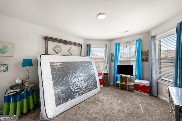 bedroom with dark colored carpet and multiple windows