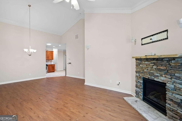 unfurnished living room with hardwood / wood-style floors, ceiling fan with notable chandelier, a fireplace, high vaulted ceiling, and crown molding