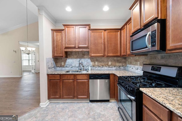 kitchen with a chandelier, pendant lighting, light stone countertops, ornamental molding, and appliances with stainless steel finishes