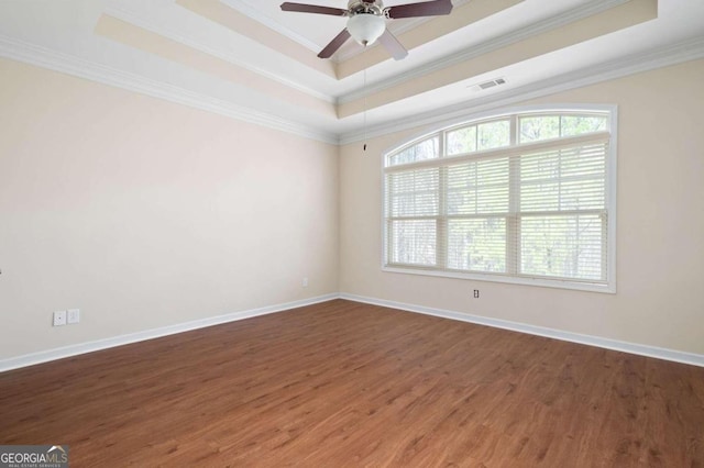 unfurnished room featuring ceiling fan, ornamental molding, a raised ceiling, and dark wood-type flooring