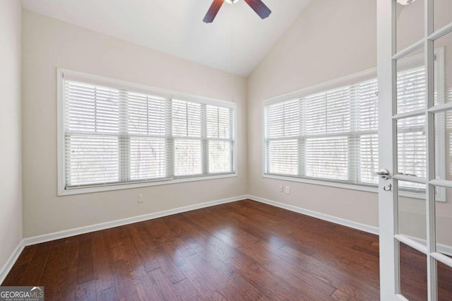 empty room featuring plenty of natural light, lofted ceiling, and dark wood-type flooring