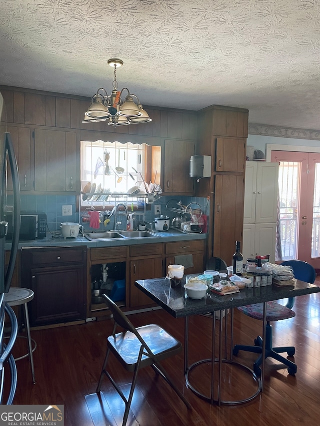 kitchen featuring a chandelier, a textured ceiling, hanging light fixtures, dark hardwood / wood-style floors, and sink