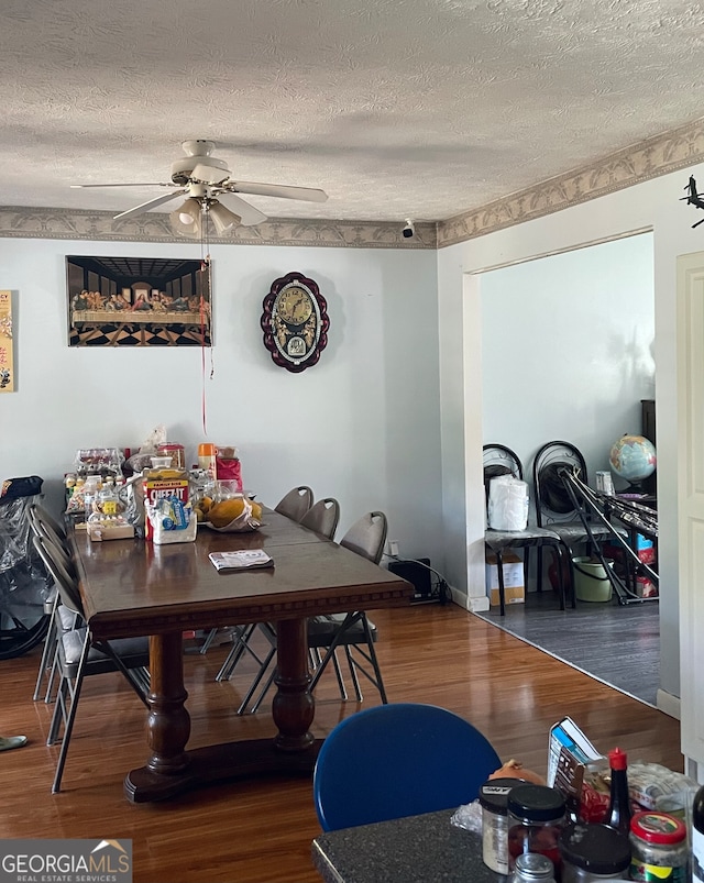 dining space with dark hardwood / wood-style flooring, ceiling fan, and a textured ceiling