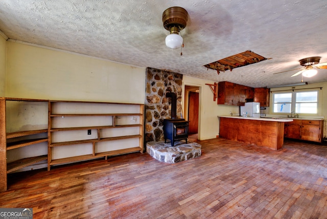 kitchen with ceiling fan, a wood stove, white refrigerator, dark hardwood / wood-style flooring, and a textured ceiling