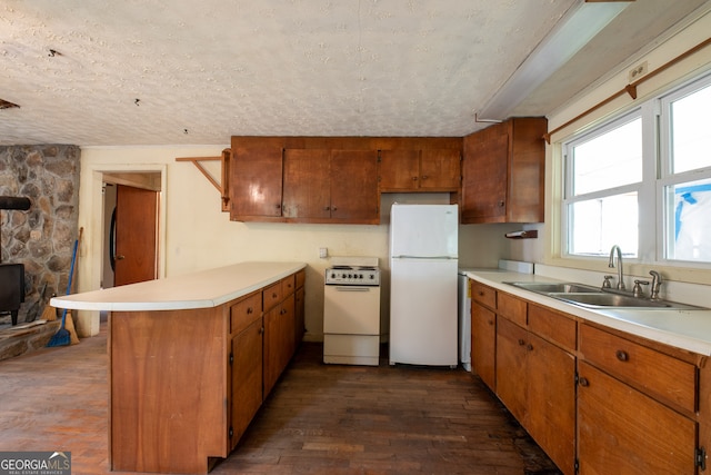 kitchen featuring sink, white appliances, dark hardwood / wood-style floors, and a textured ceiling