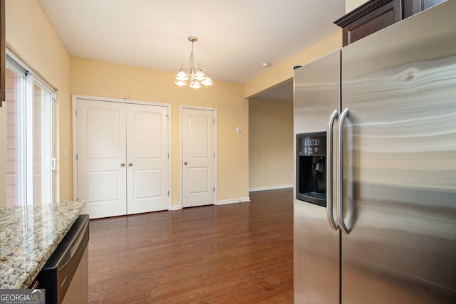 kitchen with dark hardwood / wood-style floors, hanging light fixtures, appliances with stainless steel finishes, a chandelier, and light stone countertops