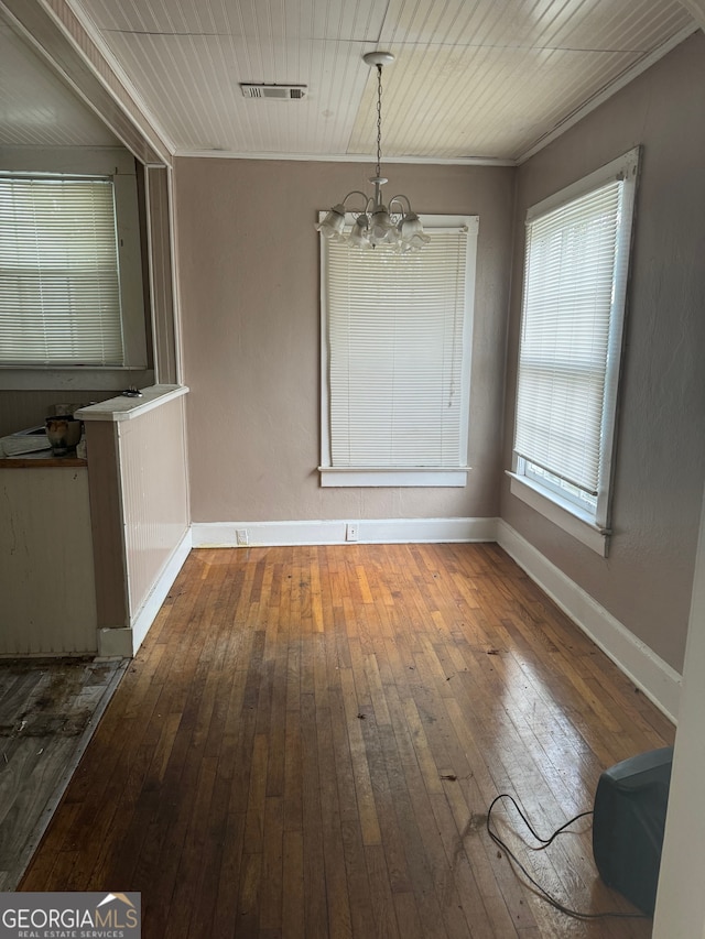 unfurnished dining area featuring dark hardwood / wood-style flooring, an inviting chandelier, and ornamental molding