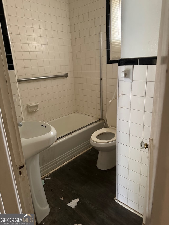 bathroom featuring combined bath / shower with glass door, wood-type flooring, toilet, and tile walls