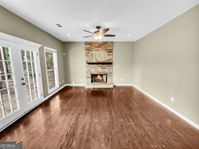 unfurnished living room featuring dark hardwood / wood-style floors, french doors, ceiling fan, and a fireplace