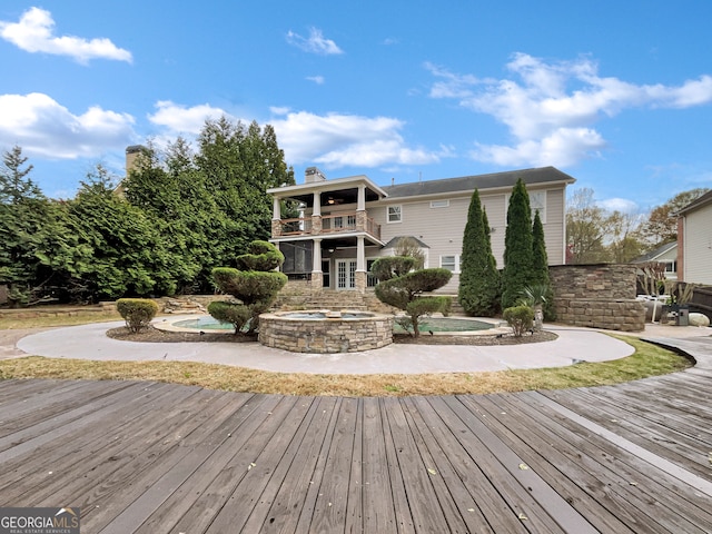 rear view of property featuring a balcony, a jacuzzi, and a patio