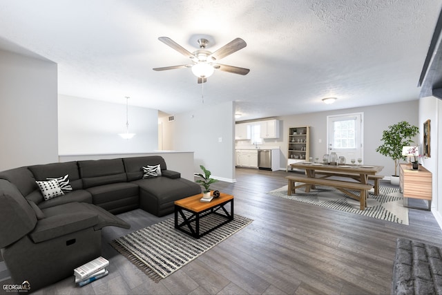 living area featuring visible vents, dark wood-type flooring, a textured ceiling, baseboards, and ceiling fan