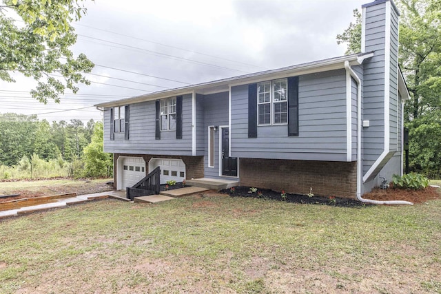 raised ranch featuring a front lawn, an attached garage, brick siding, and a chimney