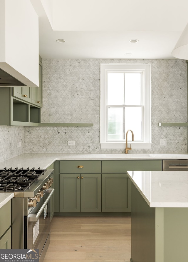 kitchen featuring decorative backsplash, light hardwood / wood-style flooring, high end stove, and green cabinets