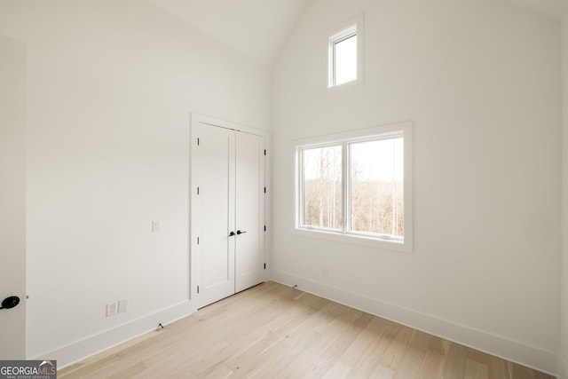 empty room featuring lofted ceiling, light hardwood / wood-style floors, and a wealth of natural light